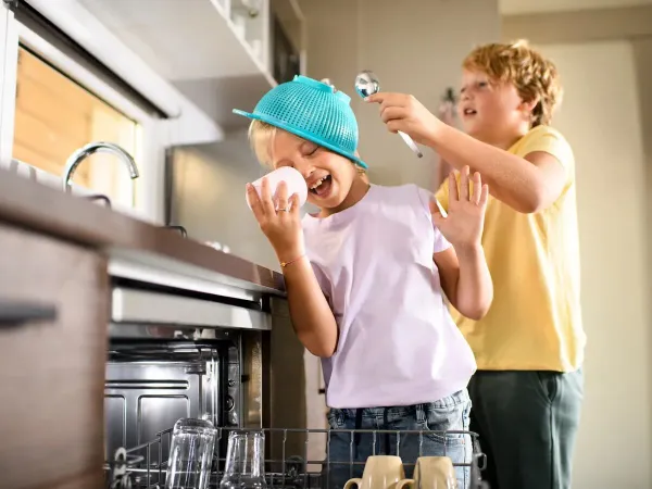 Kinderen ruimen de vaatwasser in van de Roan stacaravan Supreme met 2 badkamers.