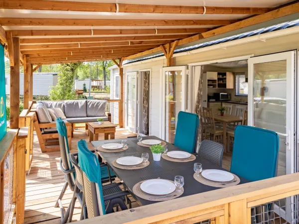 Het ruime terras van de Comfort Lounge is ingericht met een tafel, stoelen en een comfortabele loungebank.