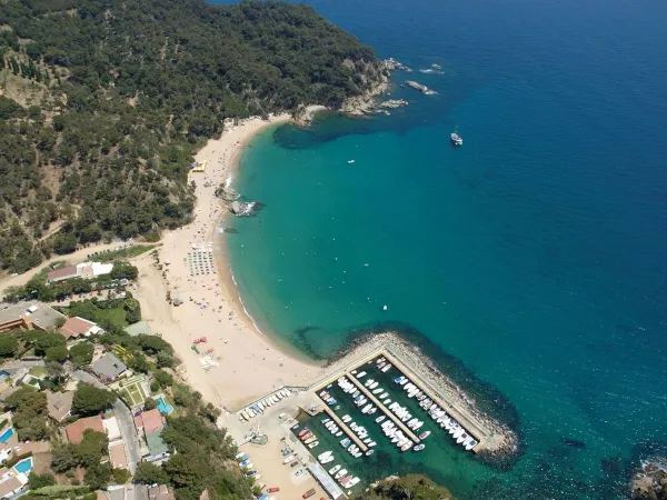 Overzicht strand en haven bij Roan camping Cala Canyelles.