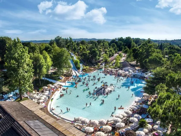 Overzicht lagune zwembad met glijheuvels en glijbanen op Roan camping hu Altomincio village.