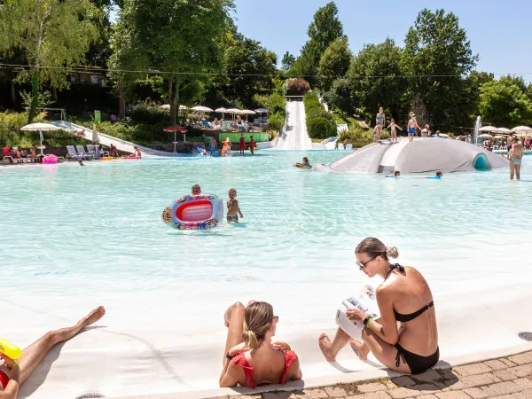 Ouders en kinderen genieten van lagune zwembad op Roan camping hu Altomincio village.