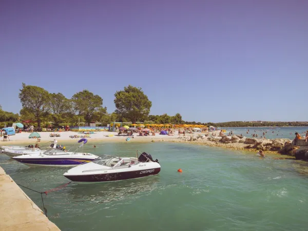 Strand met pier en bootjes op Roan camping Bi Village.