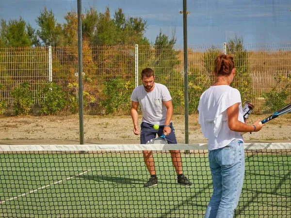 2 personen spelen een potje tennis op Roan camping Les Dunes.