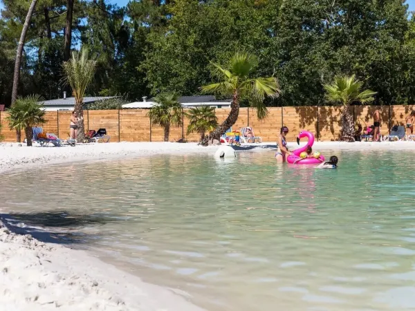 Mensen die zonnenbaden bij het lagunebad van Roan camping La Clairière.