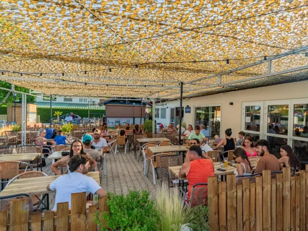 Een gezellig vol terras op Roan camping Château de Galaure.