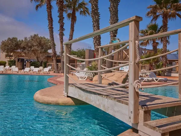 Bruggetje en ligbedden bij het zwembad op Roan camping Le Petit Mousse.