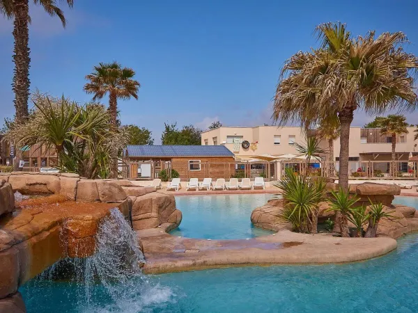 Mooie beplanting bij het zwembad met waterval op Roan camping Le Petit Mousse.