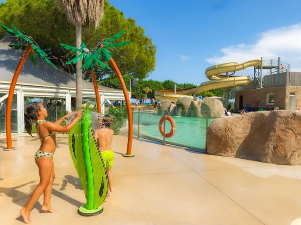 Kinderen hebben plezier bij de watersproeiers bij Roan camping Arinella Bianca.