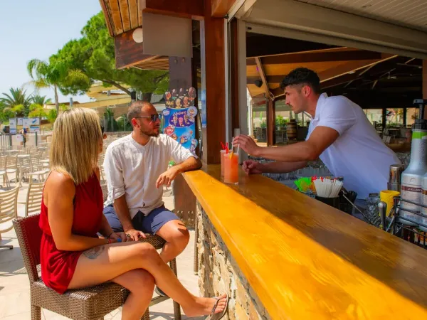 Man en vrouw bestellen een lekkere cocktail aan de bar op Roan camping Arinella Bianca.